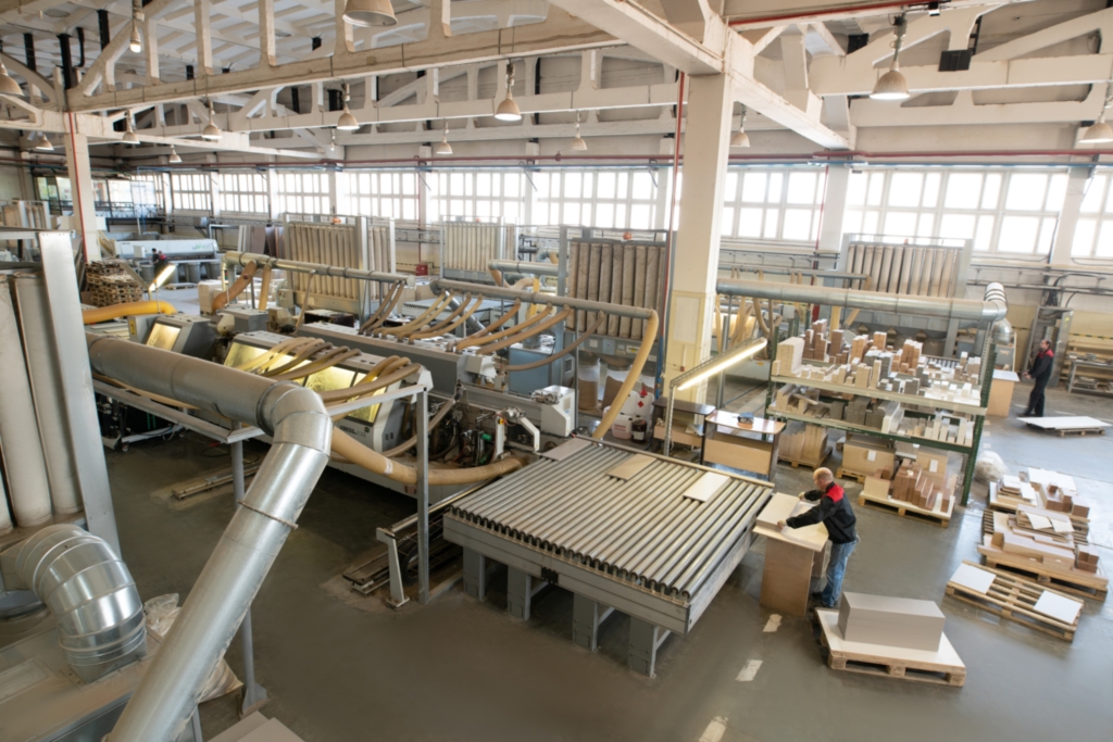 Machine cutting chipboard parts in factory workshop