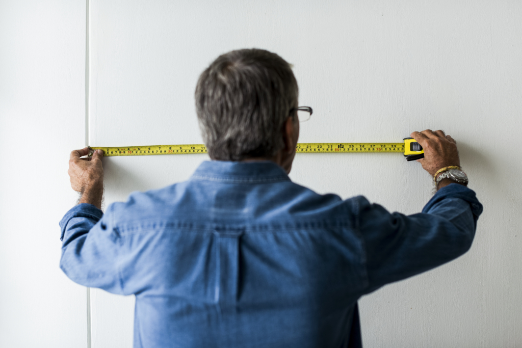 Man measuring the wall with a measuring tape